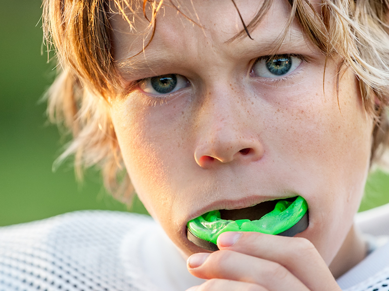 Child placing a mouthguard over their teeth
