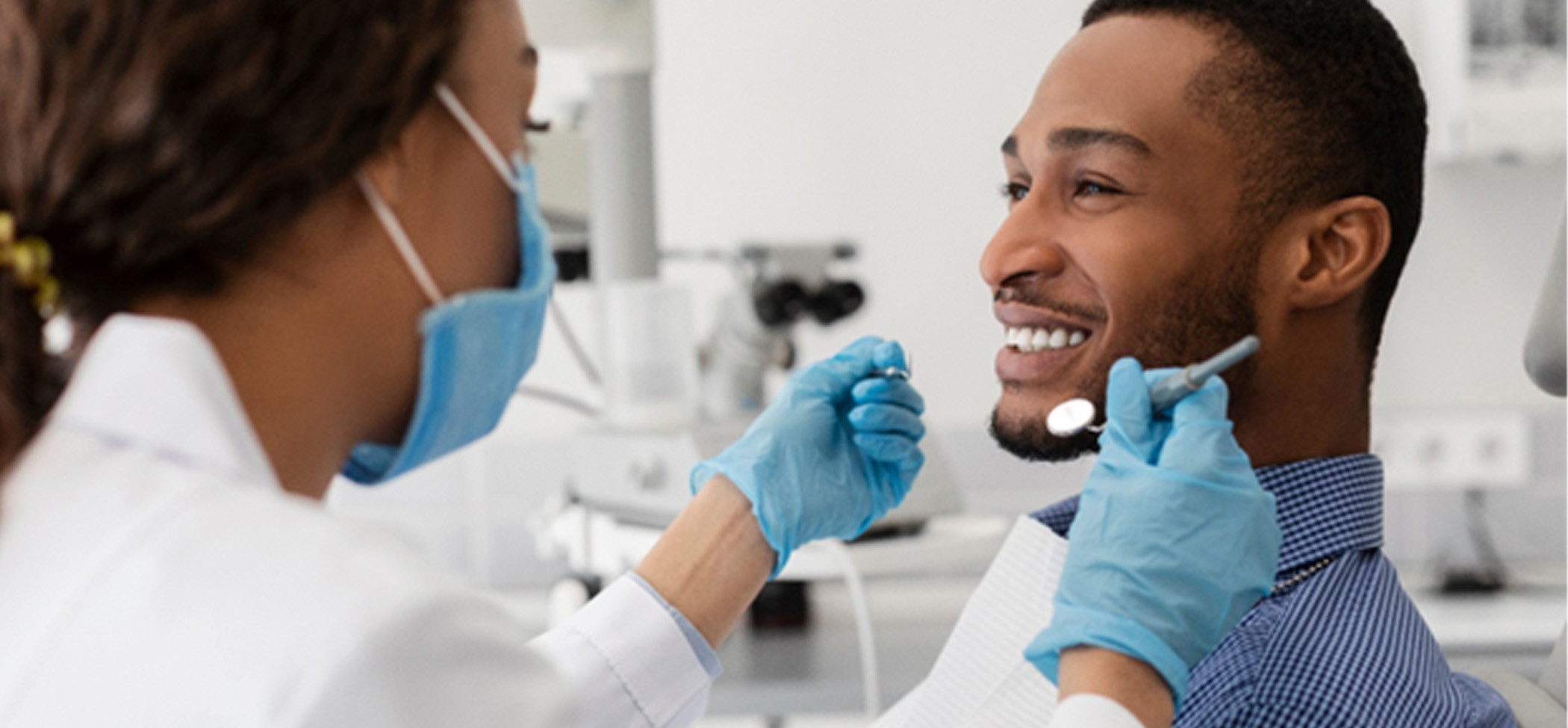 A young, African-American man smiling toward his dentist