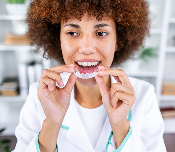 Person placing a clear aligner over their teeth
