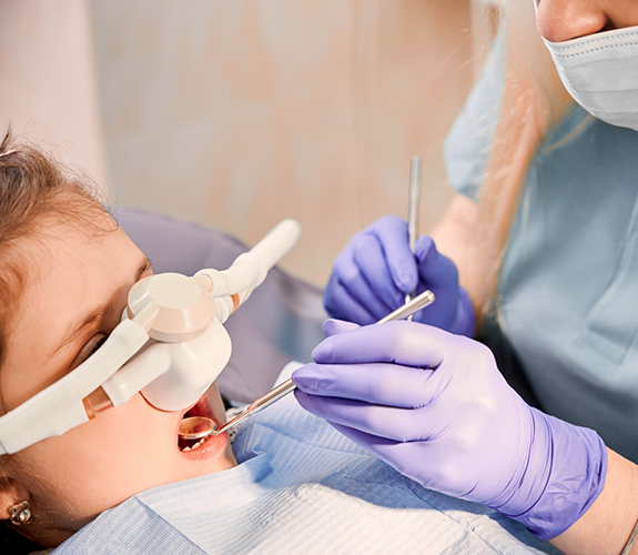 Child in the dental chair with a nitrous oxide mask over their nose