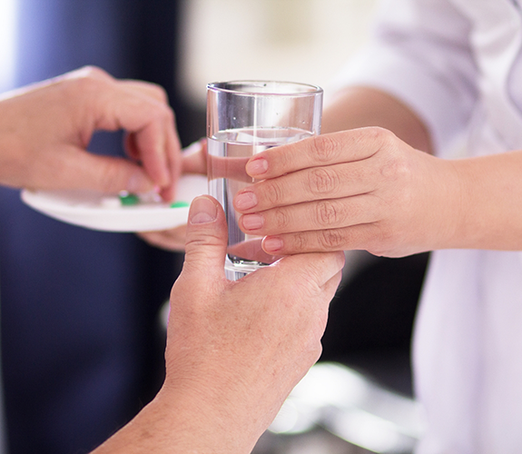 Person taking a pill with a glass of water